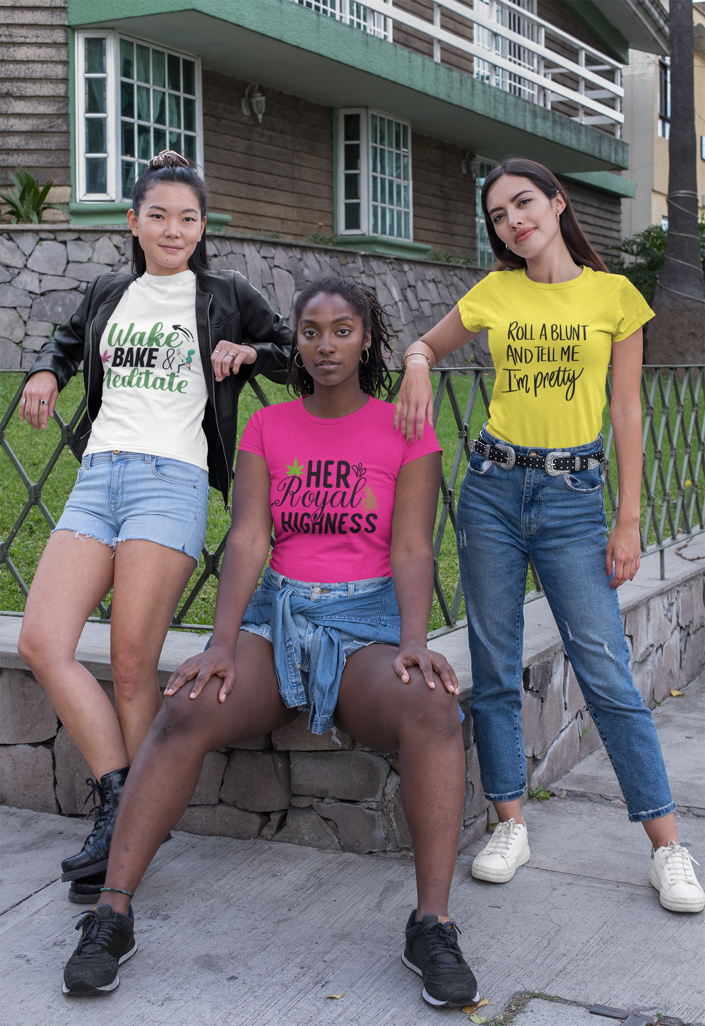 3 women on a corner with an asian woman standing on left with white t-shirt saying "Wake, Bake and Meditate", an black woman sitting in center wearing a hot pink t-shirt saying "Her Royal Highness" and a white woman standing on the right wearing a yellow t-shirt saying "Roll A Blunt and Tell Me I'm Pretty"